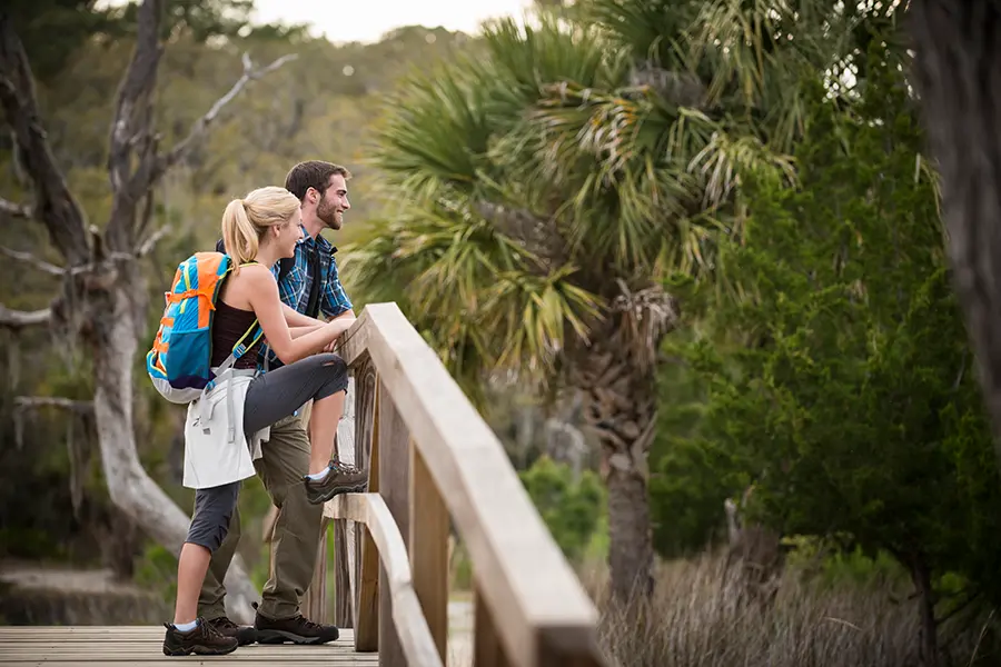 Young couple backpacking along a boardwalk in a Florida swamp sanctuary.