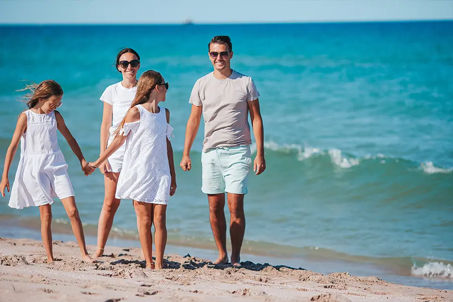 Young family relaxing on soft white Naples sand at the beach near state parks and preserves.